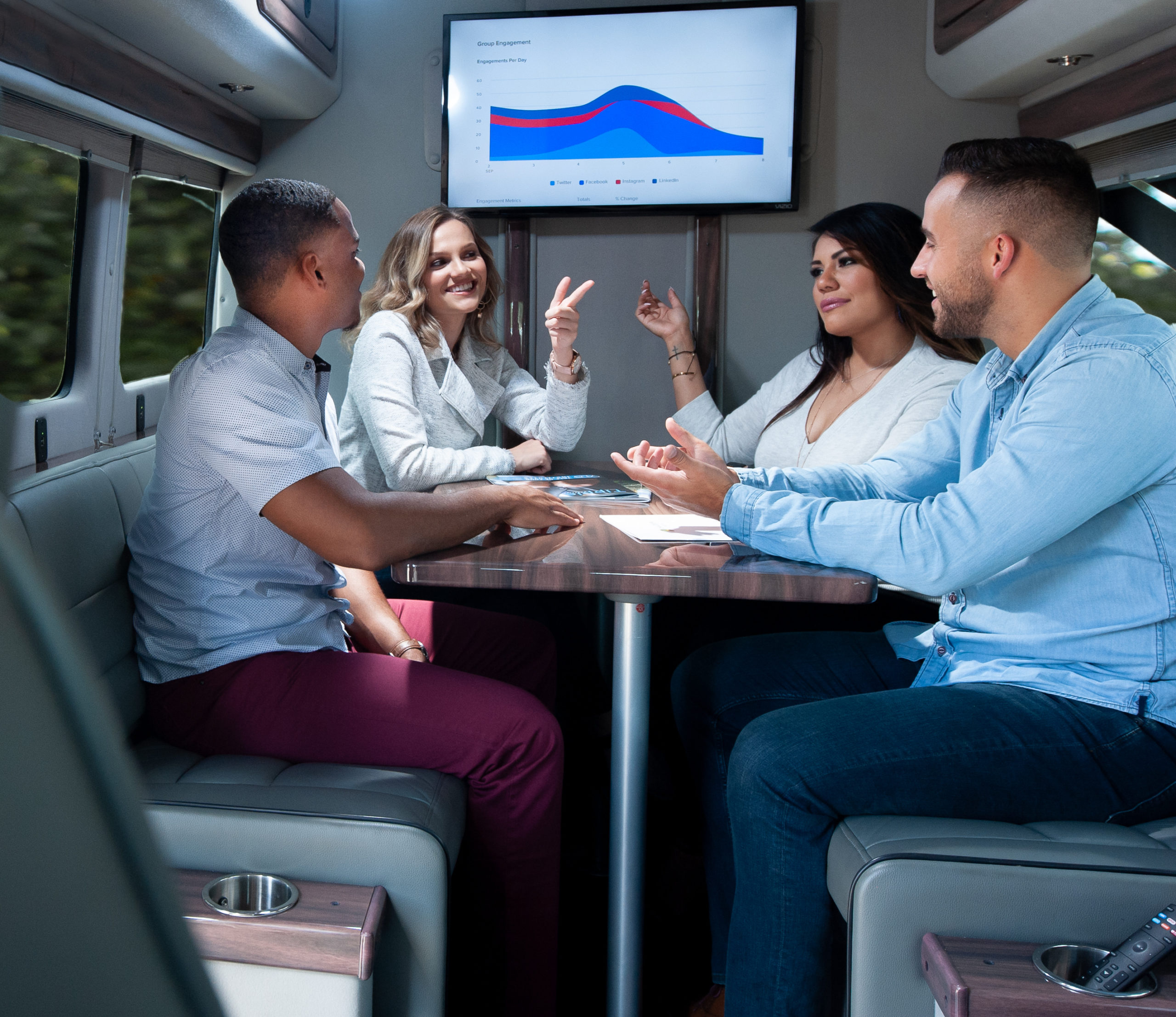 Four business people meeting around a table inside a van while traveling.